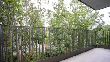Balkon mit Blick ins Grüne, umgeben von Bäumen, bietet eine ruhige Rückzugsmöglichkeit im Freien.