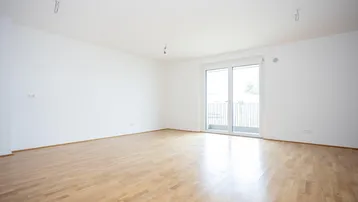 Helles, leeres Zimmer mit Parkettboden und Zugang zu einem Balkon, bereit zum Einzug.