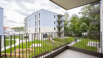 Blick von einem Balkon auf ein modernes Wohngebäude mit Spielplatz und Grünflächen.