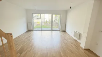 Helles Wohnzimmer mit Parkettboden, großen Fenstern und Zugang zum Gartenbereich.