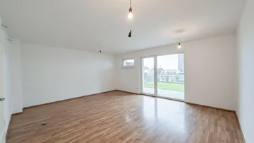Helles Wohnzimmer mit Parkettboden und Zugang zum Garten durch große Schiebetüren.