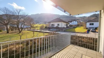 Sonniger Balkon mit Fliesenboden und weitem Blick auf die umliegende Landschaft und Berge.