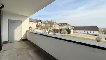 Geräumiger Balkon mit Fliesenboden und Blick auf die umliegende Wohngegend und Grünflächen.