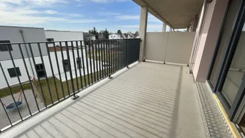 Geräumiger Balkon mit Metallgeländer und Blick auf den Innenhof der Wohnanlage.