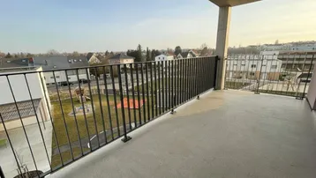 Geräumiger Balkon mit Blick auf die umliegende Wohnsiedlung und einen Spielplatz.