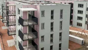 Vogelperspektive auf eine moderne Wohnsiedlung mit farbenfrohen Gebäuden und Außenbereichen.