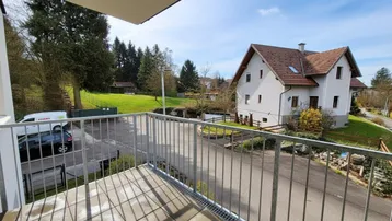 Balkon mit Fliesenboden und Metallgeländer bietet einen weiten Blick auf die umliegende Wohngegend und viel Grün.