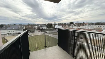 Balkon mit Metallgeländer und Blick auf die umliegende Wohngegend und den Horizont.