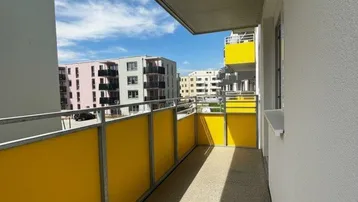 Langer Balkon mit gelben Sichtschutzelementen und Blick auf umliegende Gebäude.