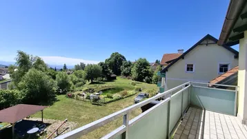 Geräumiger Balkon mit Fliesenboden und Blick auf den Garten mit Teich und die umliegende Landschaft.