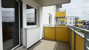 Heller Balkon mit gelben Brüstungselementen und Blick auf die umliegenden Gebäude.