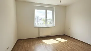 Geräumiges Schlafzimmer mit Laminatboden, Fenster und Blick ins Grüne.