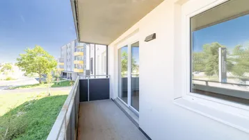 Heller Balkon mit Blick ins Grüne und auf die umliegende Wohnbebauung eines Neubaus.