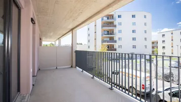 Geräumiger Balkon mit Betonboden und Metallgeländer, bietet einen weiten Blick auf umliegende Gebäude.
