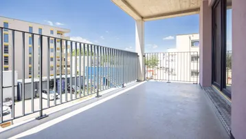 Geräumiger Balkon mit modernem Metallgeländer und Blick auf die umliegenden Gebäude.