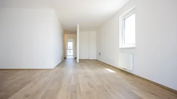 Heller, leerer Wohnbereich mit modernem Laminatboden und einem großen Fenster.