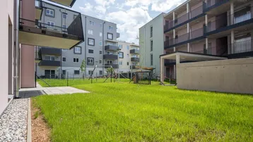 Grüner Innenhof mit Spielplatz zwischen modernen Wohngebäuden, ideal für Familien.
