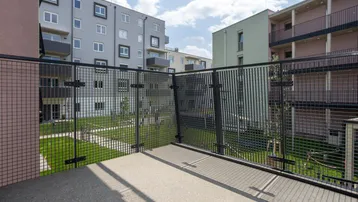 Balkon mit Metallgeländer und Blick auf den begrünten Innenhof der Wohnanlage.