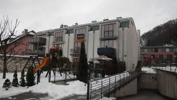 Mehrfamilienhaus mit moderner Architektur, Balkonen, Spielplatz und Zugang zur Tiefgarage im Winter.