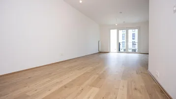 Großes Wohnzimmer mit hellem Laminatboden und breiter Schiebetür, die zu einem Außenbereich führt.