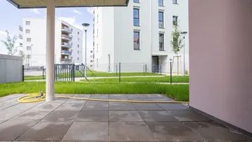 Gepflasterte Terrasse im Erdgeschoss mit Blick auf die umliegenden Neubauten.