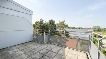 Geräumiger Balkon mit Fliesenboden und Metallgeländer, bietet einen weiten Blick ins Grüne.