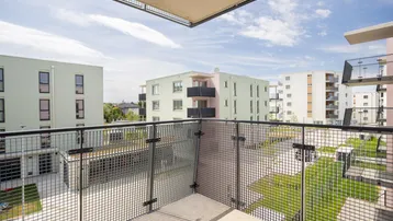 Geräumiger Balkon mit Metallgeländer und Blick auf die umliegenden Neubauten und Grünflächen.