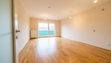 Heller, leerer Raum mit schönem Holzboden, großen Fenstern und direktem Zugang zu einem Balkon.