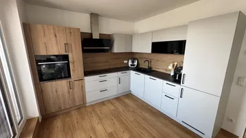 Moderne Küche mit Holz- und weißen Fronten, schwarzer Arbeitsplatte und integrierten Geräten.