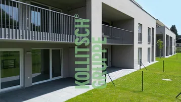 Moderne Wohnanlage mit hellgrauer Fassade, Balkonen und Terrassen, umgeben von Grünflächen.