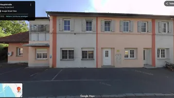 Gebäudefassade mit mehreren Fenstern und einem Eingangsbereich, aufgenommen aus der Google Street View Perspektive.