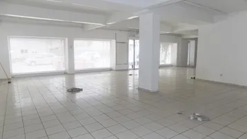 Großer, leerer Geschäftsraum mit Fliesenboden und großen Fenstern zur Straße hin.