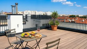 Geräumige Dachterrasse mit Holzboden, Sitzgelegenheiten und weitem Blick über die Stadt.