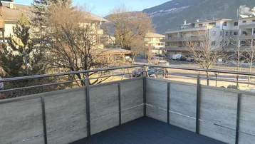 Geräumiger Balkon mit Holzboden und Blick auf die umliegende Berglandschaft.