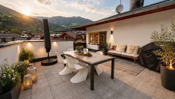 Geräumige Dachterrasse mit modernen Gartenmöbeln, Bergblick und Abendsonne.