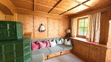 Gemütliches Wohnzimmer im alpinen Stil mit Holztäfelung, Kachelofen und integrierter Sitzbank.