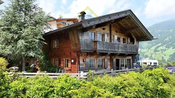 Traditionelles Holzchalet mit Balkon und Blick auf die umliegende Berglandschaft.