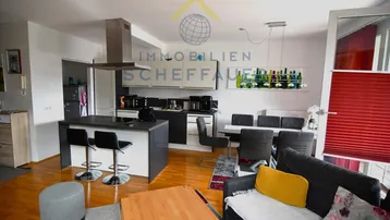 Heller offener Wohn- und Essbereich mit integrierter Küche, Holzboden und moderner Einrichtung.