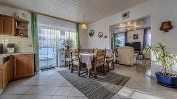 Geräumige Wohnküche mit traditionellen Holzschränken, Essbereich und Blick in das angrenzende Wohnzimmer.