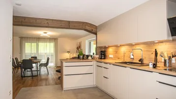 Moderne Einbauküche mit hellen Fronten, Holzarbeitsplatte und offenem Blick zum Essbereich.