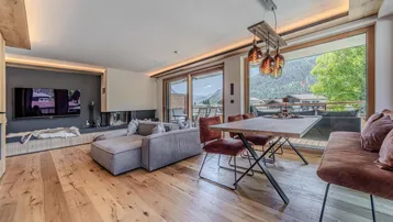 Geräumiger Wohn-Essbereich mit Holzboden, Kamin und Zugang zum Balkon mit Bergblick.