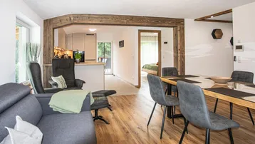 Heller Wohn- und Essbereich mit offener Küche, Holzbalken und modernem Interieur.