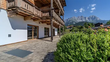 Geräumige Terrasse mit Holzbalkonen und herrlichem Bergblick, umgeben von grüner Natur.