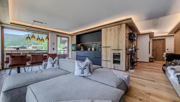 Geräumiger offener Wohnbereich mit moderner Küche, Essbereich und gemütlichem Sofa, umgeben von Holzelementen.
