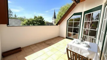 Heller Balkon mit Fliesenboden und Blick auf die Kirche, ausgestattet mit einem kleinen Tisch.