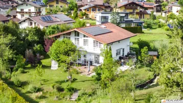 Luftaufnahme des Einfamilienhauses mit Photovoltaikanlage auf dem Dach und großem Garten.