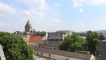 Stadtansicht mit historischen Gebäuden und Kirchturm unter blauem Himmel.