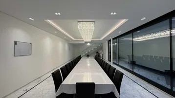 Großer, eleganter Speisesaal mit langer Tafel, Marmorboden und beeindruckendem Kristallleuchter.
