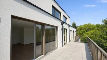 Geräumige Terrasse mit Fliesenboden und Zugang zu den Innenräumen, umgeben von viel Grün.