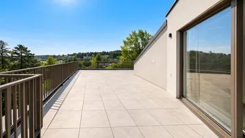 Geräumige Dachterrasse mit Fliesenboden und weitem Blick über die grüne Landschaft unter strahlendem Sonnenschein.